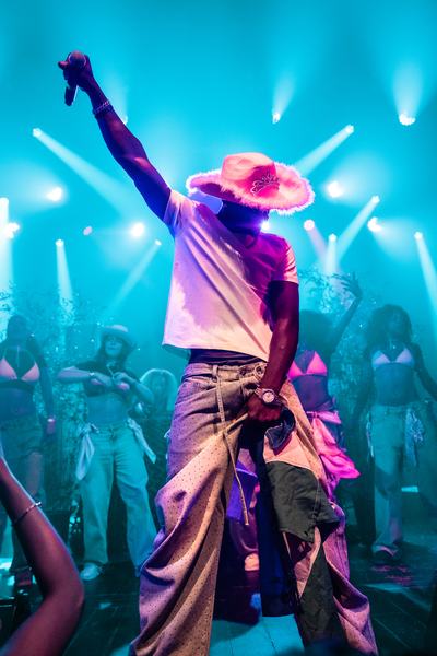 TJ WEST on stage in a cowboy hat, microphone raised